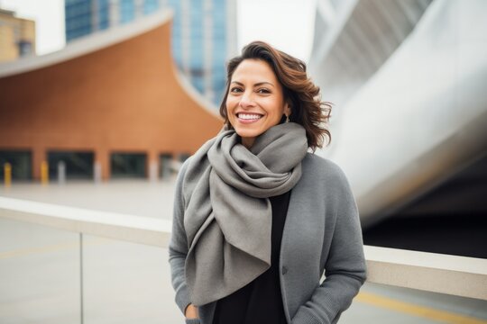 Portrait photography of a Colombian woman in her 40s wearing a cozy sweater against a modern architectural background