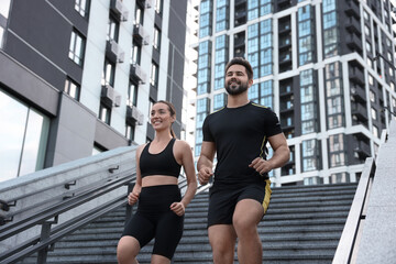 Healthy lifestyle. Happy couple running on steps outdoors, low angle view