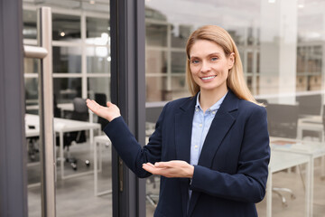 Happy real estate agent in suit inviting inside