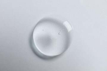Drop of cosmetic oil on white background, top view