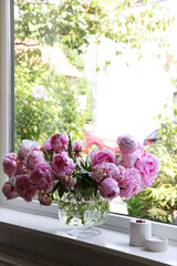 Beautiful pink peonies in vase on window sill, space for text. Interior design