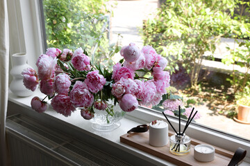 Beautiful pink peonies in vase on window sill. Interior design