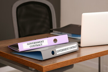 Folders with Government Contract labels on desk in office