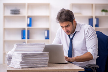 Obraz premium Young male employee and too much work in the office