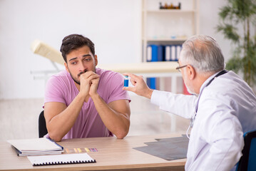 Fototapeta premium Young male patient visiting old male doctor
