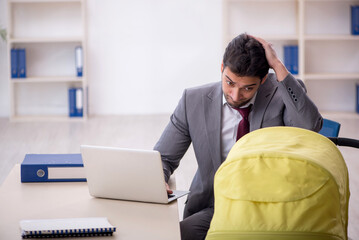 Young male employee looking after newborn at workplace