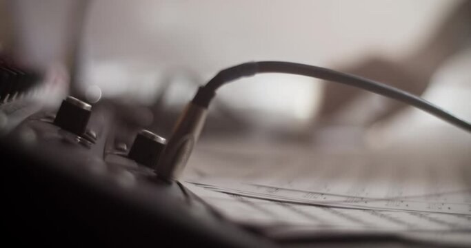 Crop hand plugging cable into guitar amplifier in studio