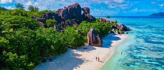 Anse Source d'Argent, La Digue Seychelles, a young couple of men and women on a tropical beach during a luxury vacation in Seychelles. Tropical beach Anse Source d'Argent, La Digue Seychelles - obrazy, fototapety, plakaty