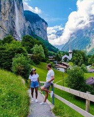 men and women visiting Lauterbrunnen valley with a gorgeous waterfall and Swiss Alps in the background, Berner Oberland, Switzerland, Europe during summer