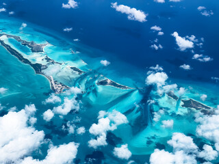 Aerial view of islands in Caribbean Sea displaying vibrant green and blue waters with white clouds