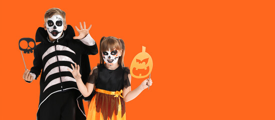Little children in Halloween costumes on orange background with space for text
