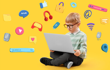 Sitting little boy with laptop on yellow background