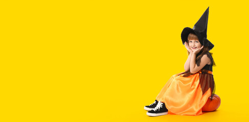 Cute little girl dressed as witch for Halloween sitting on pumpkin against yellow background with space for text