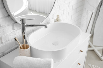 White sink with bath accessories on chest of drawers in bathroom, closeup