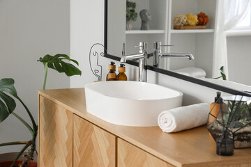 White sink with bath accessories on chest of drawers in room