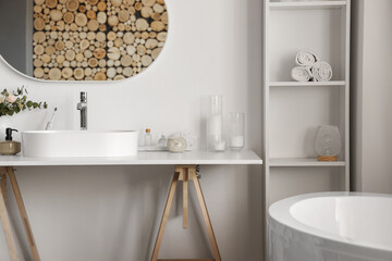 Interior of light bathroom with white sink, bathtub and shelving unit