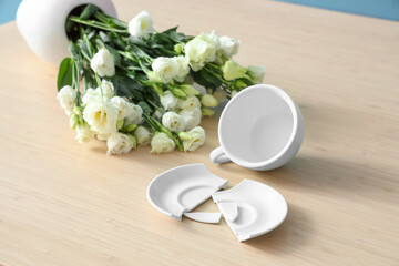 Broken plate with bowl and roses on table in messy room, closeup