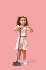 Thoughtful little girl with broom on pink background