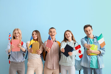 Group of students with books and flags of different countries on blue background