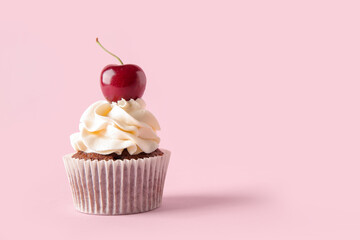 Tasty cherry cupcake on pink background