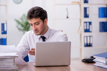 Young male employee and too much work in the office