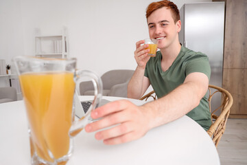Fototapeta premium Young man drinking juice in kitchen