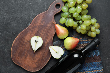 Wooden board with fruits and bottle of wine on grunge black kitchen table