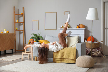 Happy young woman lying on sofa at home