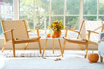 Interior of living room with autumn bouquet on table and armchairs