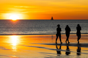 Ladies walking along Broome beach at sunset