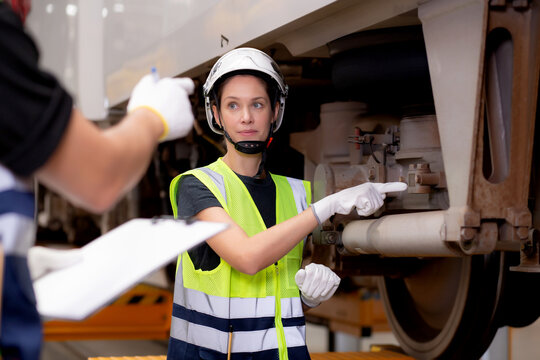 Young caucasian engineer man and woman or worker checking electric train for planning maintenance looking document on clipboard in station, transport and infrastructure, inspector check transport.