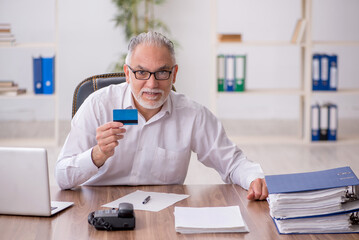 Old male employee holding credit card