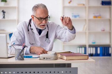 Old male doctor working in the clinic