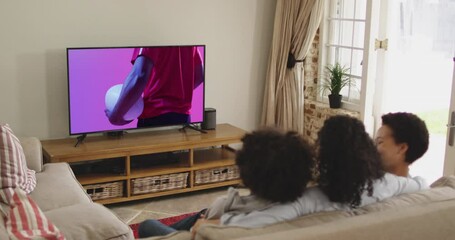 Biracial family watching tv with african american male rugby player with ball on screen - Powered by Adobe