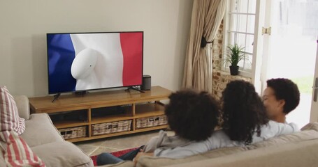 Biracial family watching tv with rugby ball on flag of france on screen - Powered by Adobe