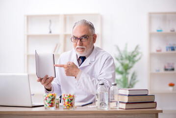Old male doctor holding book in the clinic