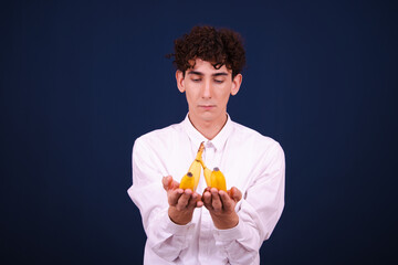 Funny curly guy eating a banana and posing on a blue background.