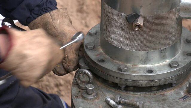 Close up worker tighten nut and bolt install flange pipe in water treatment pond. Fragment of a large diameter main pipe. Urban water system
