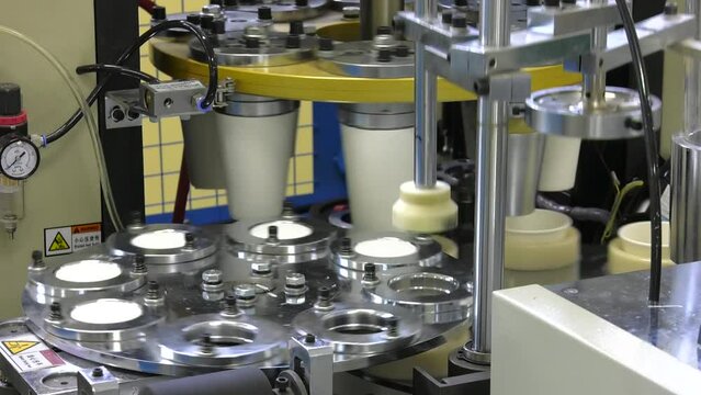 Paper cup machine engaged in industrial production. Close up view. Production of paper cups out of cardboard for coffee on modern equipment.
