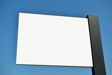 Low angle view of blank billboard with blue vibrant sky at background