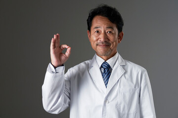 OKポーズをする中年の医師　黒背景