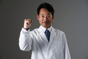 ガッツポーズをする中年の医師　黒背景