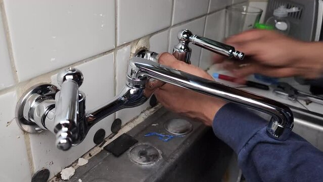 Plumber installing new faucet in kitchen sink