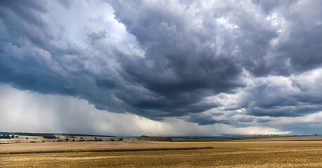 Starkregen und dunkler Wolken ziehen über Äcker und Felder