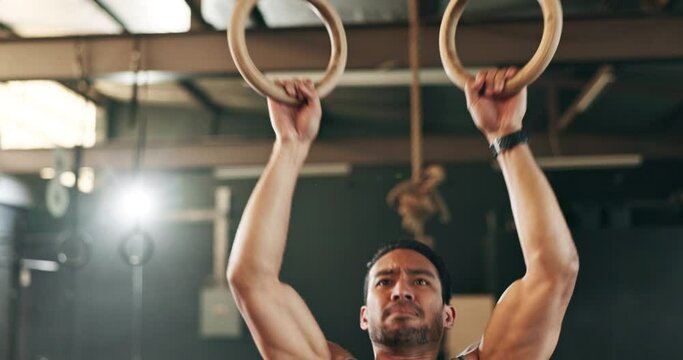 Fitness, gymnastics and man doing a pull up exercise for arm muscle training or workout in gym. Sports, bodybuilding and Indian male athlete doing an intense strength challenge in a health center.