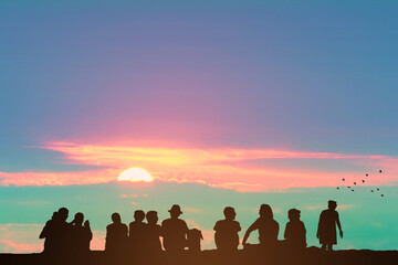 Silhouette people sitting on the stone floor and sunrise on the colorful sky orange cloud and birds flying