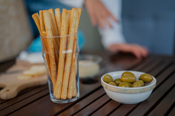 Tasty italian bread sticks and olives snacks on picnic wooden table