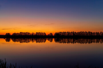 beautiful orange-yellow sunset on the lake in spring