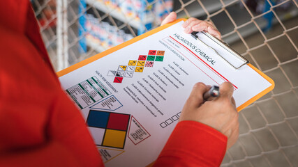 A worker is checking on the hazardous chemical material information form with background of...