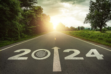 Goals, targets in New year 2024 or straightforward concept. Text 2024 and dartboard with dart icon on the road in the middle of asphalt road at sunset. Life, business planning, challenge, strategies. - obrazy, fototapety, plakaty